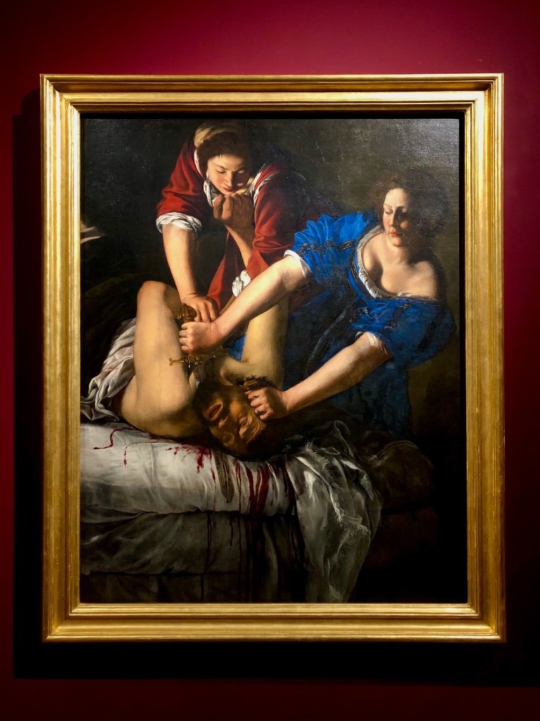Artemisia Gentileschi's painting of Judith Beheading Holofernes: Judith and her young handmaid both pin the general to his bed as Judith cuts off his head with a knife. Though he holds off the handmaid with one arm, his eyes are closed as if he's about to fall limp.