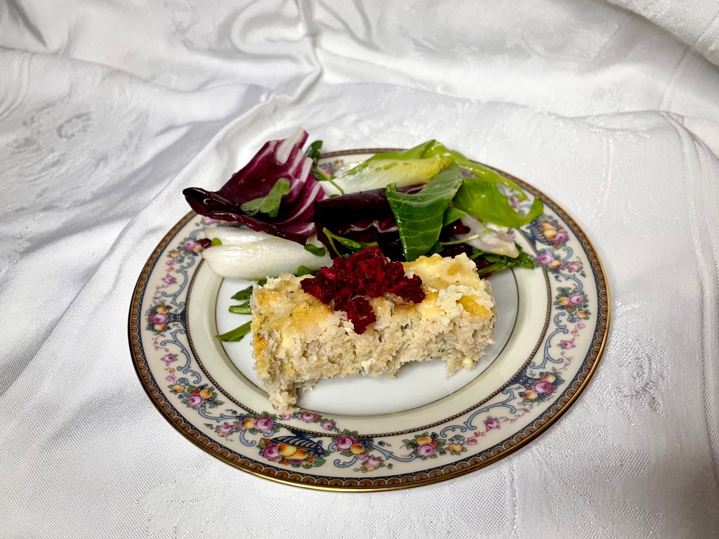 A plate of homemade gefilte fish with red chrain (beets and horseradish) and a bitter greens salad.